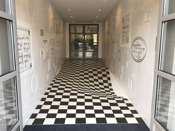 A picture of a hallway with a floor tiled in such a way that it looks like it is melting out from underneath.